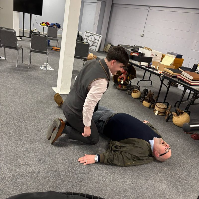 A learner practising CPR chest compressions on a resuscitation manikin during training