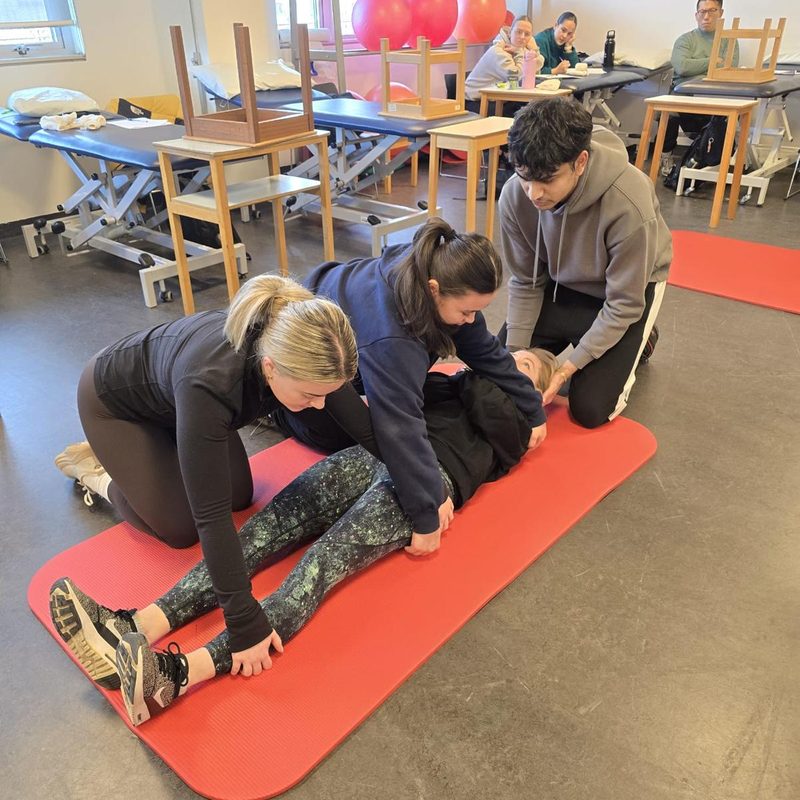 A group practising CPR on manikins laid out on training mats during an on-site session